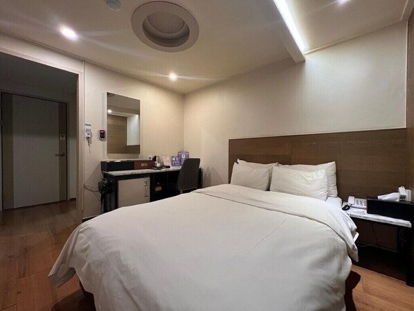 A hotel room with a large bed, a desk with a computer, and a mirror on the wall. - Ssumhotel (Suwon)