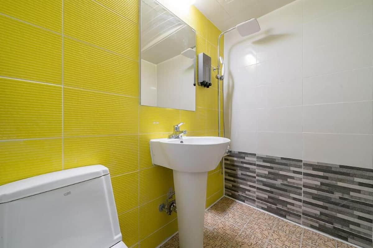 A bathroom with yellow tiled walls, a white sink, and a shower area.
