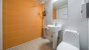 Egy fürdőszoba narancssárga csempékkel borított falakkal, fehér mosdókagylóval és WC-vel.