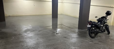 A parking garage with a motorcycle parked near a pillar.