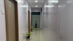 Un couloir doté d’un sol en marbre, de portes en bois et de plantes en pot.