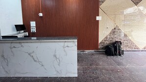 Un espace d’accueil agrémenté d’un mur en panneaux de bois, d’un comptoir de réception en marbre et d’un sol carrelé orné d’un motif géométrique.