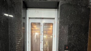 Un ascenseur doté d’une porte en verre, d’un écran numérique et d’un panneau de commande.