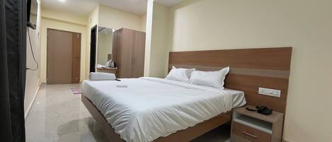A bedroom with a wooden bed, a nightstand, a wardrobe, a ceiling fan, and a mirror.