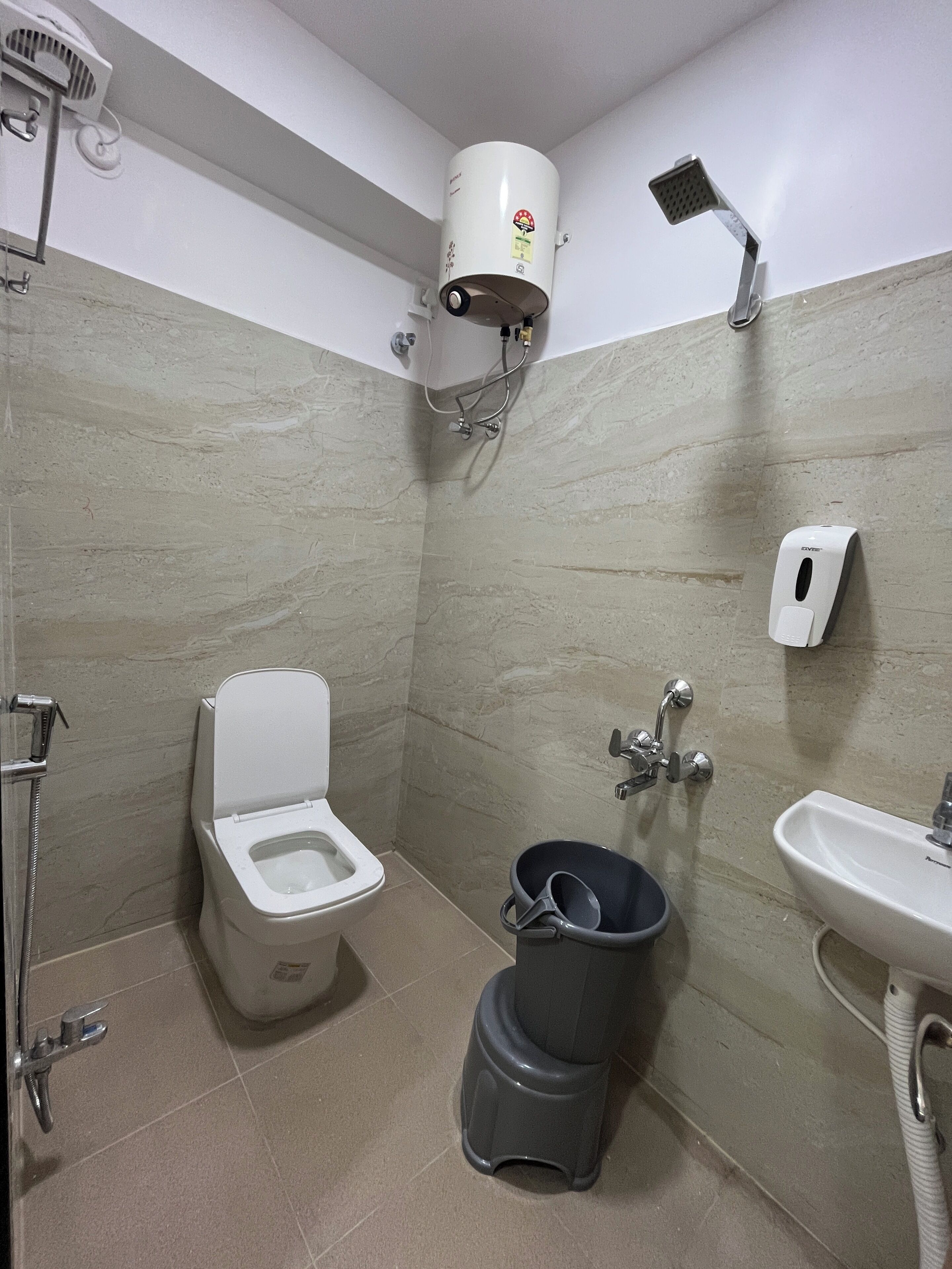 A bathroom with a toilet, bidet, hand dryer, and a small sink.
