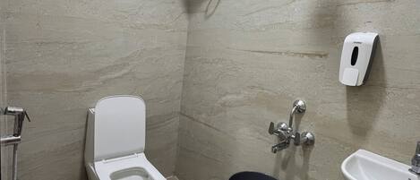 A bathroom with a toilet, bidet, hand dryer, and a small sink.
