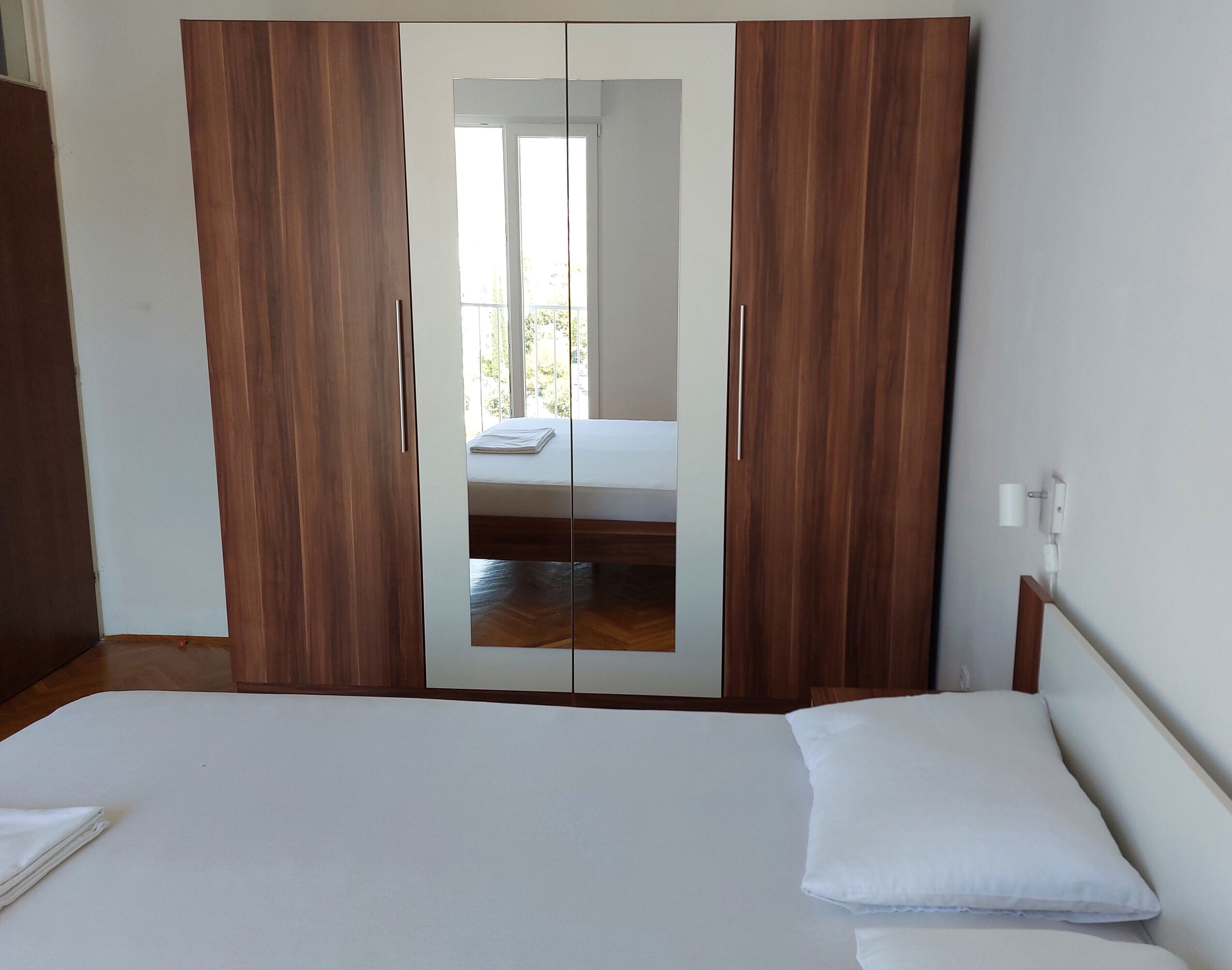 Una camera da letto con un ampio guardaroba, un letto e vista su un balcone.