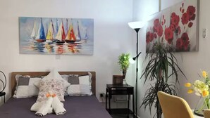 Makuuhuone, jossa on sänky, purjelaivoja kuvaava taulu, lamppu ja ruukussa oleva kasvi.