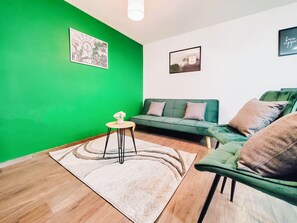 Relax in this stylish living room with a green sofa, round table, and patterned rug.