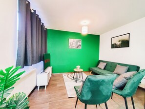 Relax in this stylish living room with a comfortable sofa, side table, and armchair, surrounded by lush greenery and elegant decor.