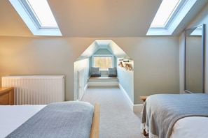 A bedroom with skylights, a bed, a radiator, and a window seat with cushions. - Host Stay Peasholm Place (Scarborough)