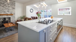 A modern kitchen with a central island, built-in oven, and pendant lighting. - Host Stay Peasholm Place (Scarborough)