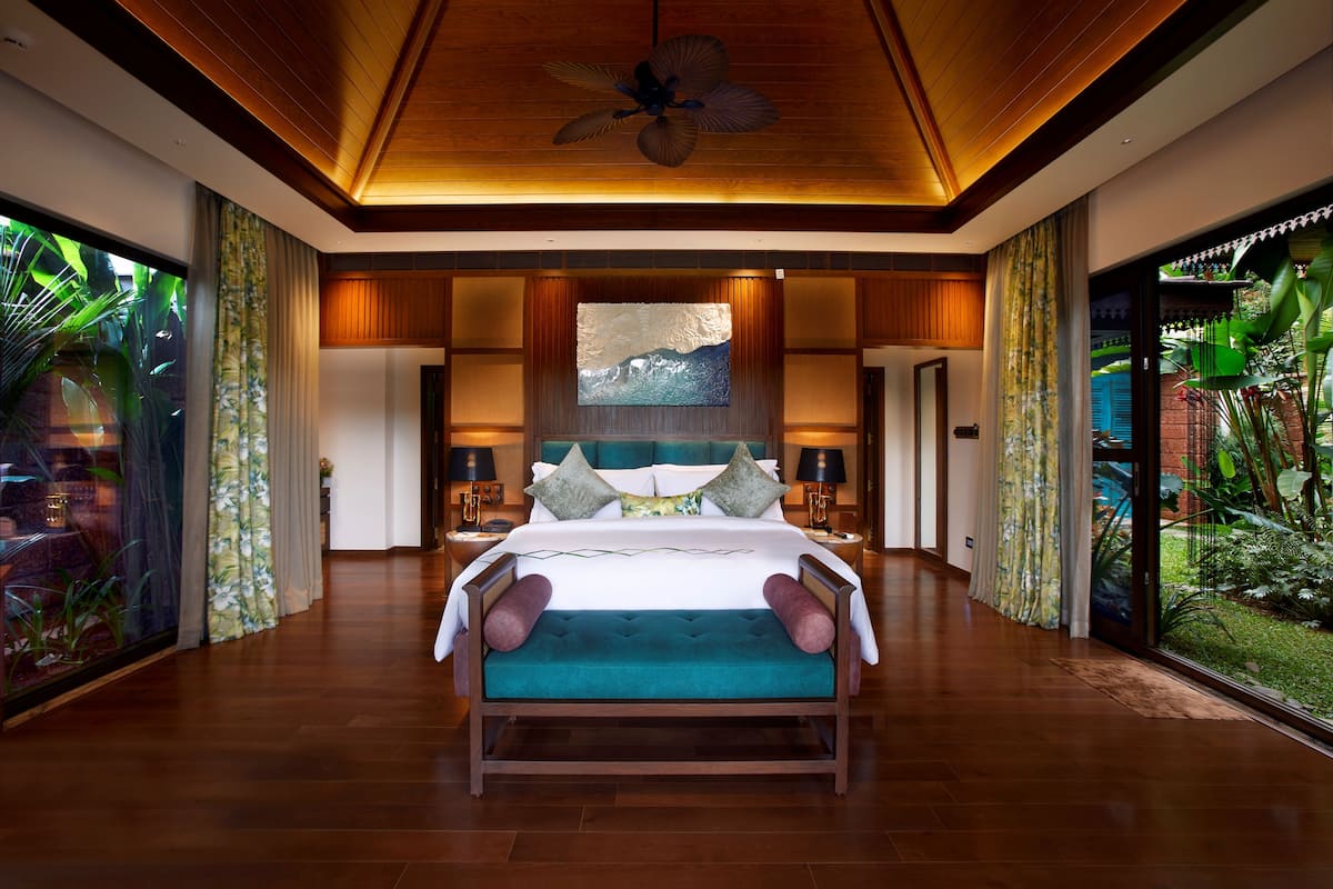 Un dormitorio amplio con una cama grande, un ventilador de techo y vistas a un jardín exuberante.
