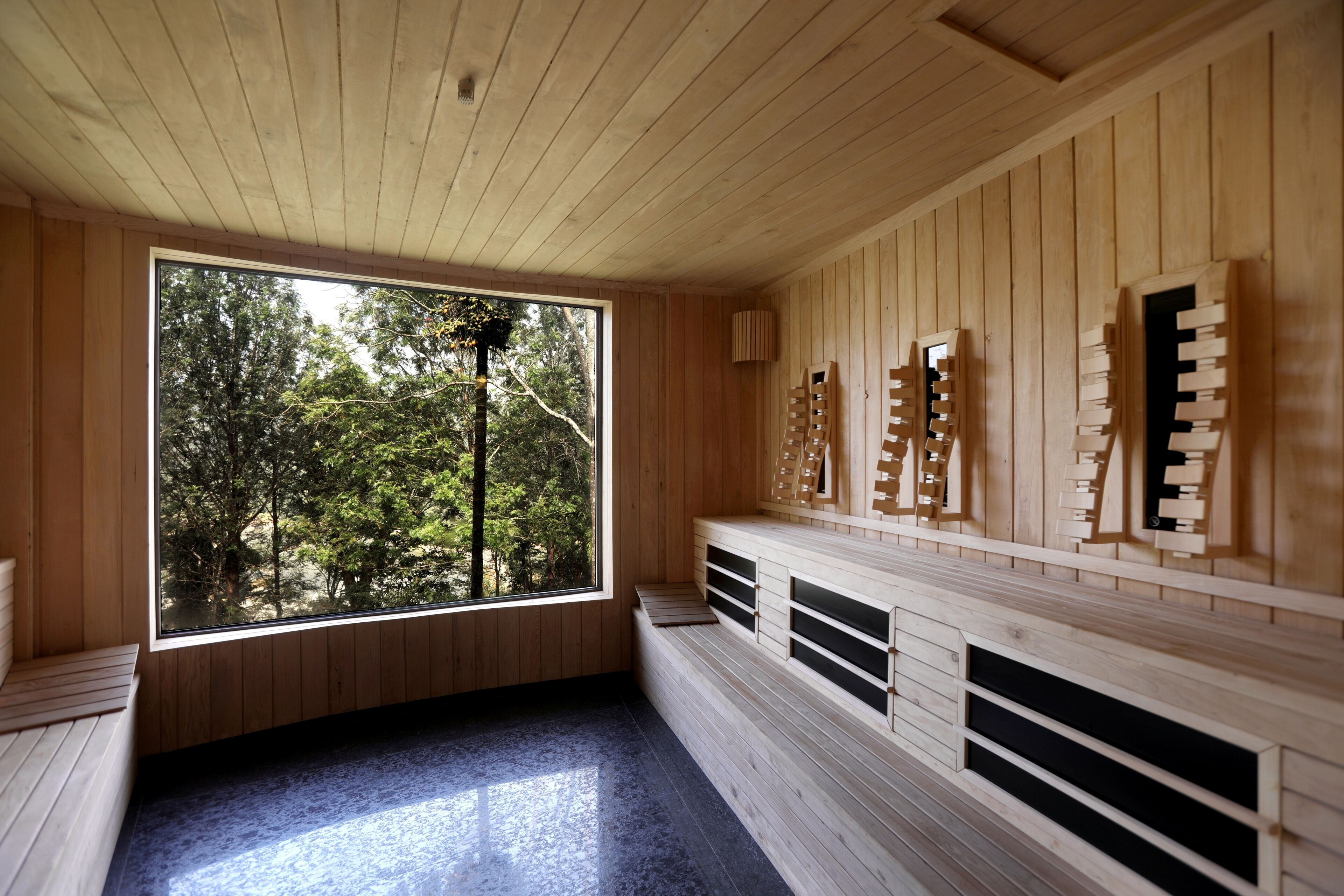 A sauna room with wooden walls, a bench, and a large window.