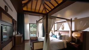 Quarto com cama de dossel, mesa de cabeceira, televisão e vista para o exterior.