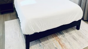 A modern bedroom with a large bed, a bedside table, a small plant, and a window with curtains. - Modern 2BR Near SJC | W/D | FirePit | Free Parking (San Jose)