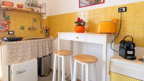 Una cuina compacta amb un rentapeus, un refrigerador petit, una cafetera i tamborets.