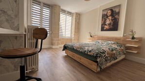 Un dormitorio con una cama de madera, una silla, un radiador y un cuadro en la pared.