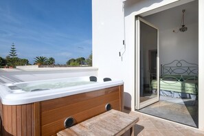 Un bain à remous avec des panneaux en bois, une table en bois et un lit avec un cadre en métal.
