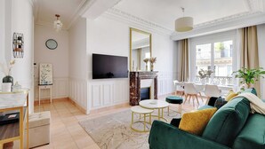 Uma sala de estar moderna com lareira, televisão e um espaço de jantar com mesa e cadeiras.