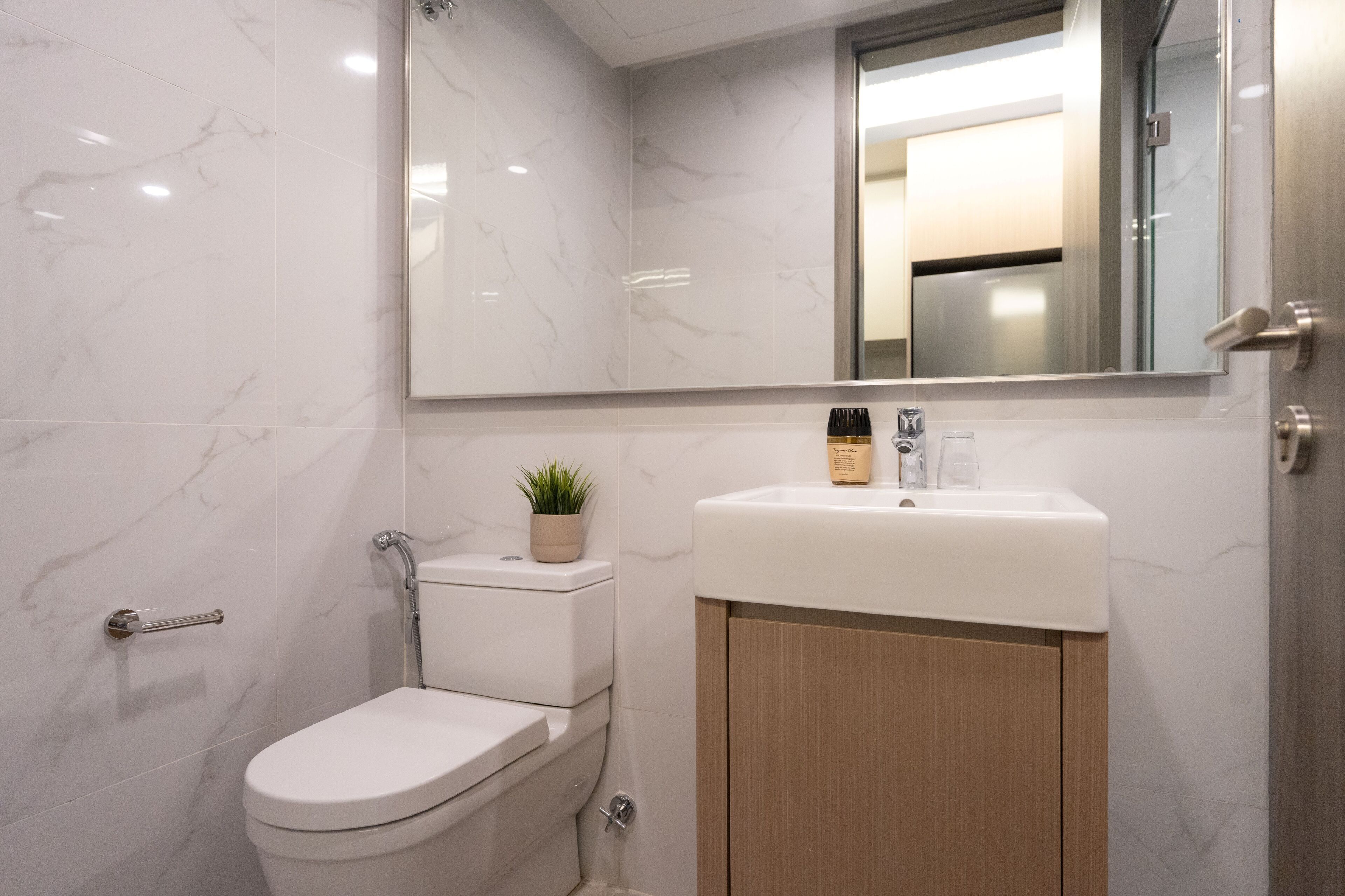 A modern bathroom with a white toilet, a sink with a mirror above, and a wooden cabinet.