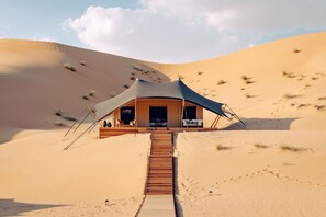 A desert tented structure with a wooden staircase leading to the entrance. - Amar Luxury Desert Ecolodge (Al 'Ajban)