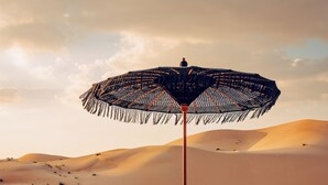Een woestijnoord met tenten, lounge fauteuils en een grote parasol.