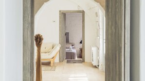 An arched doorway leading to a room with a sofa, a small table, and a vase of dried flowers.
