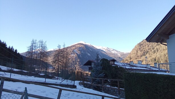 A mountainous landscape with a snow-covered ground, a wooden fence, and a building with a sloped roof. - Apartment for 8 people in a quiet area in Pellizzano - Via G. Tomaselli, 6 (Pellizzano)