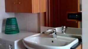 A small kitchen with wooden cabinets, a sink, a washing machine, and a green basket. - Apartment for 8 people in a quiet area in Pellizzano - Via G. Tomaselli, 6 (Pellizzano)