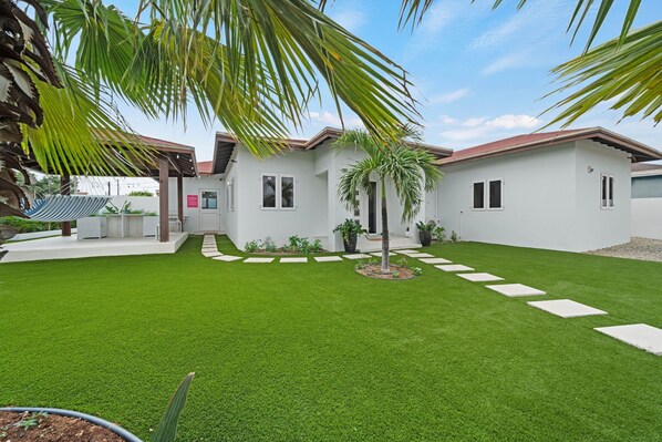 A modern house with a well-maintained lawn, a palm tree, and a pergola. - Mazurka 19 (Noord)