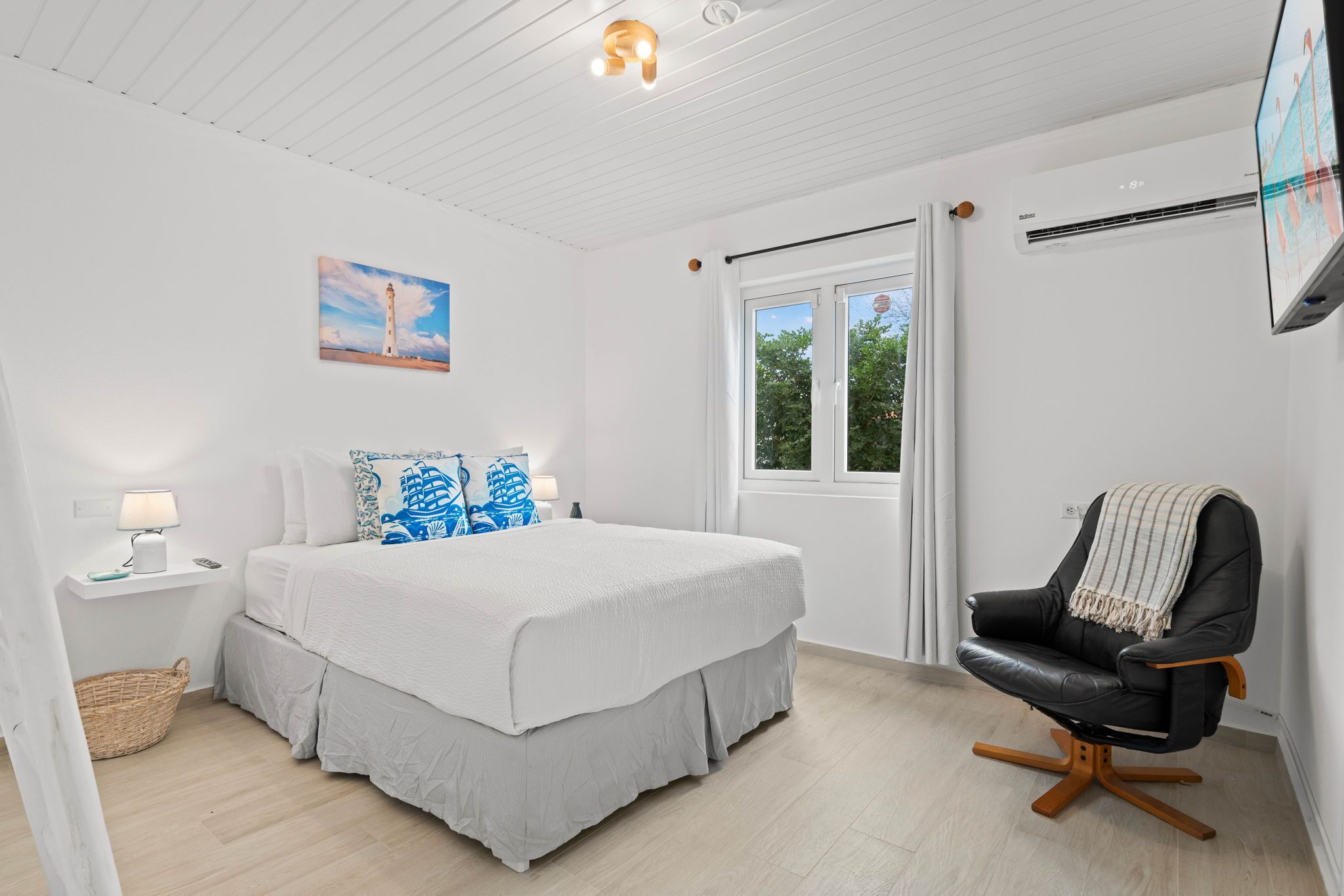 Une chambre avec un grand lit, une chaise, un tableau et une fenêtre.