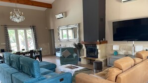 A living room with a sofa set, a fireplace, a television, and a dining area.