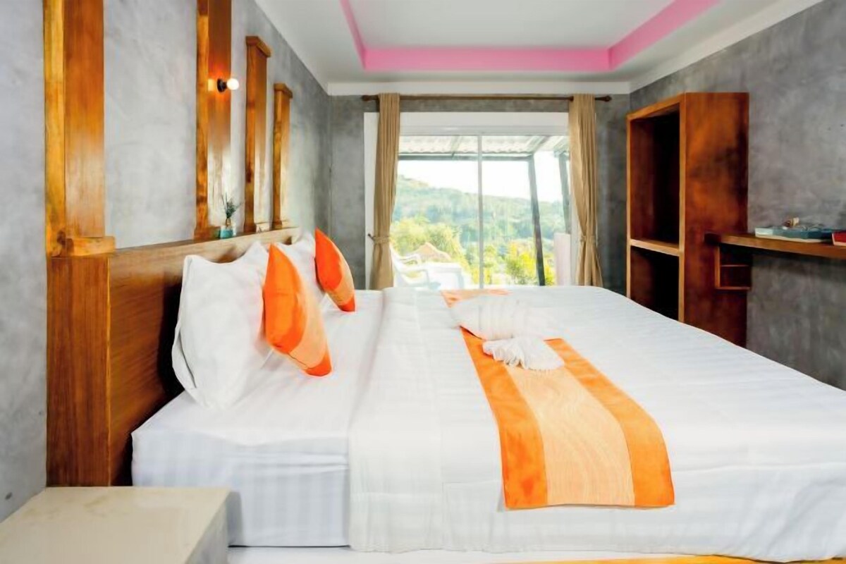 A hotel room with a large bed, wooden headboard, and a view of the outdoors.