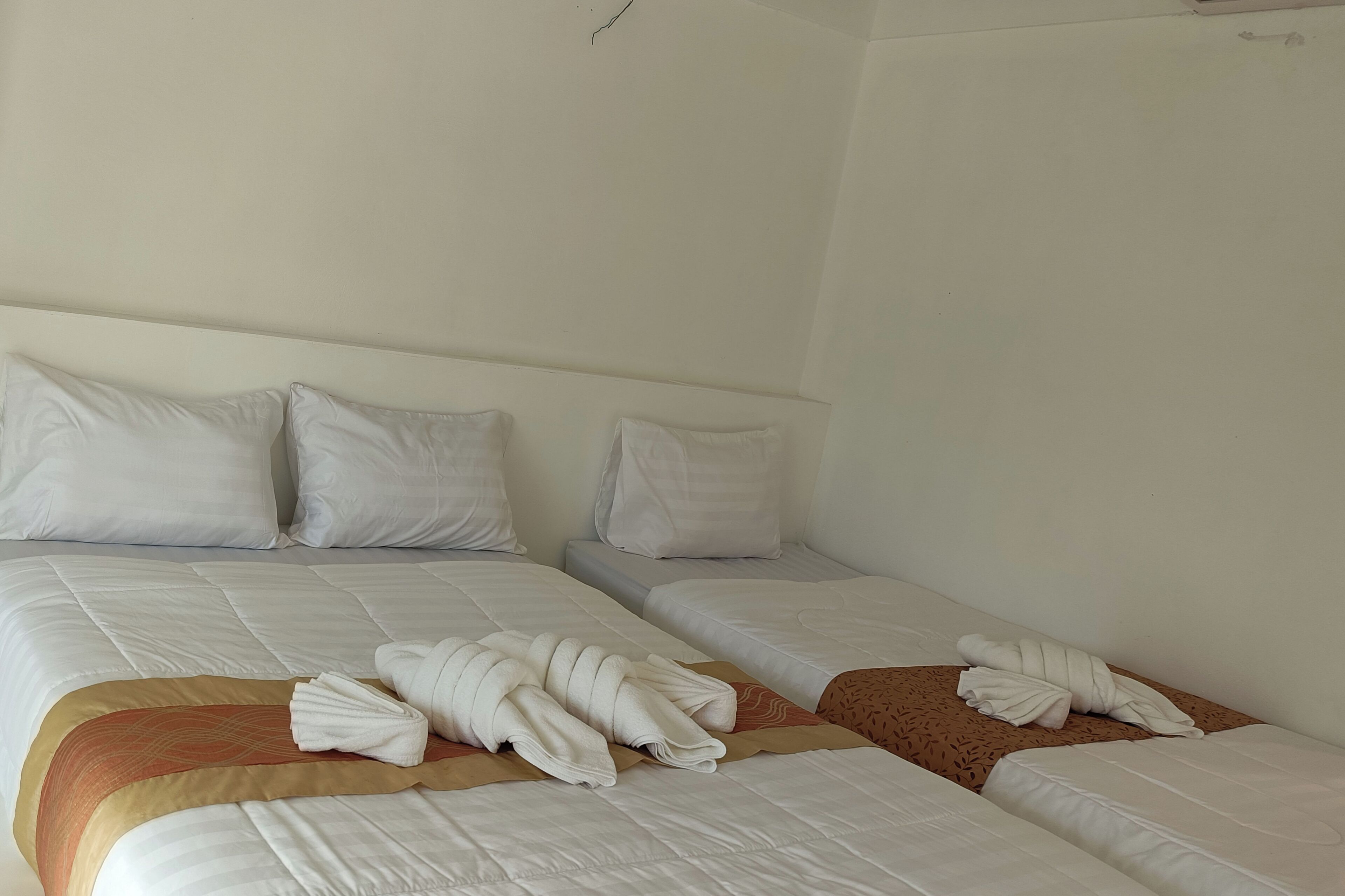 Une chambre d’hôtel avec deux lits, chacun étant équipé de draps et d’oreillers blancs.