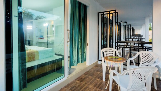 A modern hotel room with a glass door leading to a balcony, white plastic chairs, and a small table. - PhuLanta Resort (Ko Lanta)