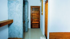 A narrow hallway with a wooden door at the end, a wooden shelf on the left, and a white wall on the right. - PhuLanta Resort (Ko Lanta)