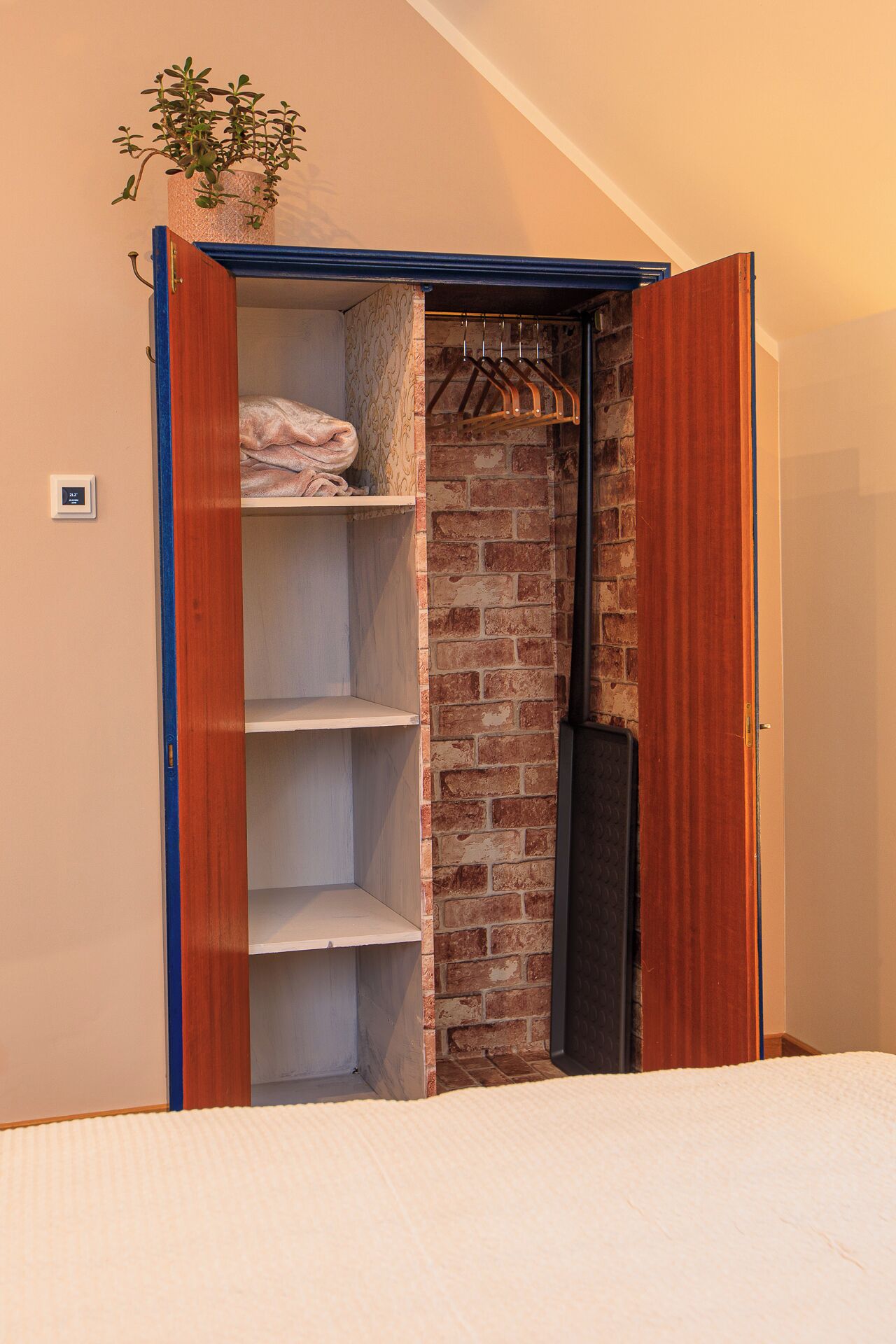 A walk-in closet with a brick wall, wooden shelves, and a hanging rack.