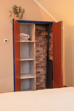 A walk-in closet with a brick wall, wooden shelves, and a hanging rack.