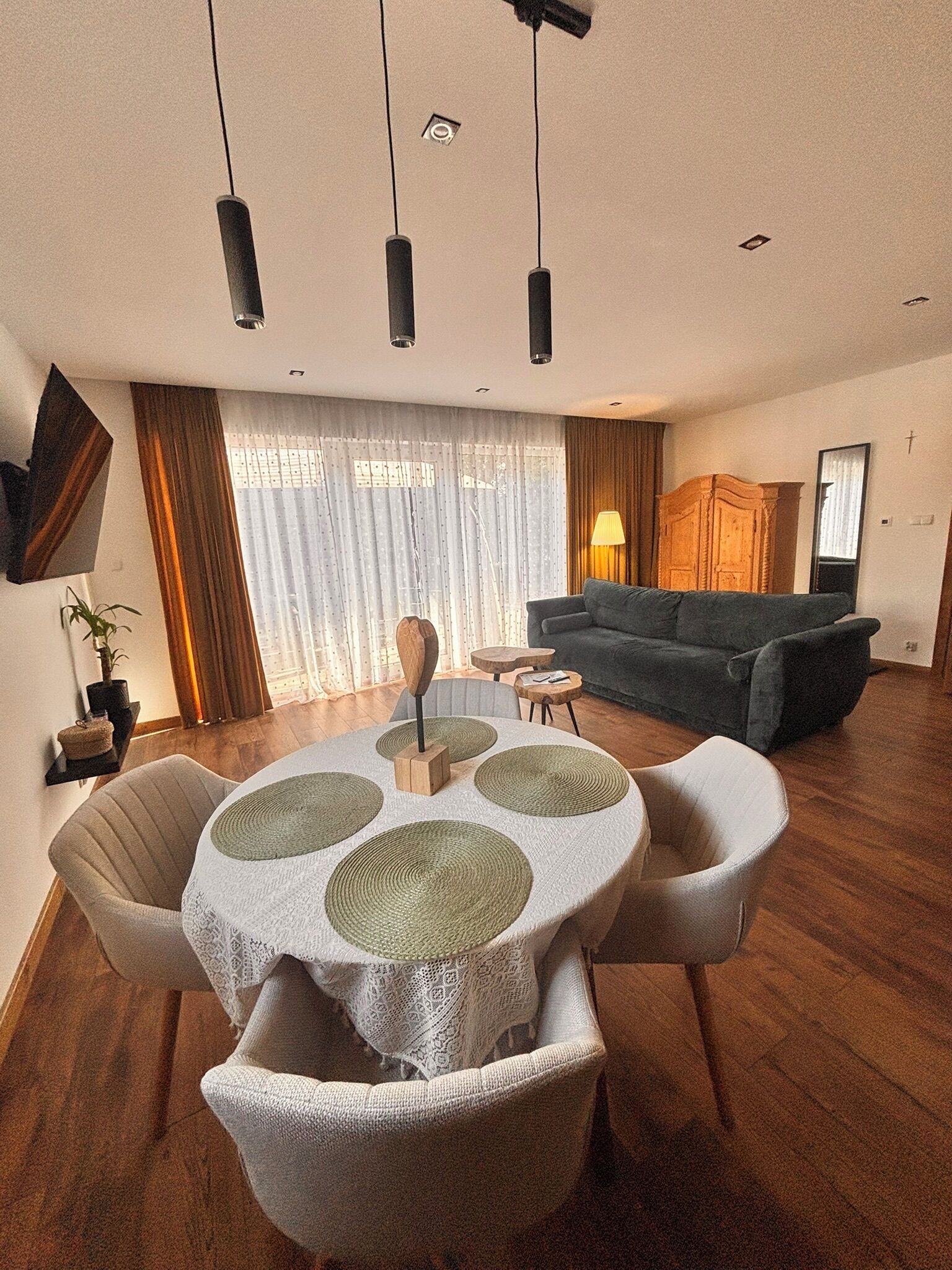A modern living room with a round table, a sofa, and a TV mounted on the wall.
