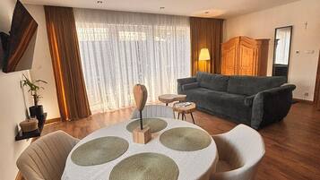 A modern living room with a round table, a sofa, and a TV mounted on the wall.