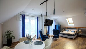 A modern room with a loft bed, a dining area with a round table, and a TV mounted on the wall.