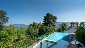 A rooftop infinity pool with a clear view of the ocean and mountains, surrounded by lush greenery and a wooden deck. - Luxury 2BR Apartment in Bluepoint 82 (Patong)