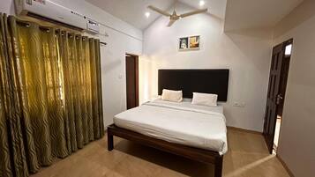 A bedroom with a bed, an air conditioning unit, a ceiling fan, and a door.