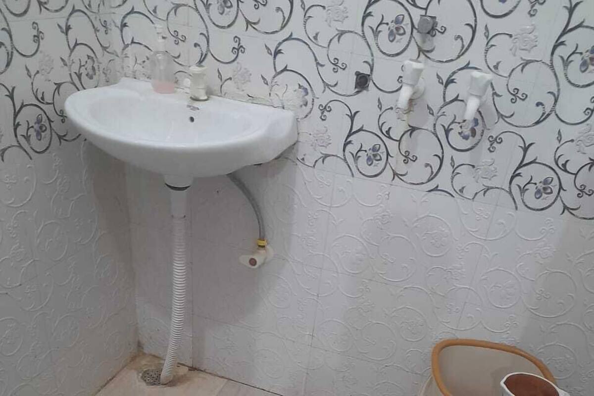 Een badkamer met een wit zuilwastafeltje, een toilet en een kleine prullenbak.