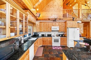 A spacious kitchen with wooden cabinets, a black countertop, and a white refrigerator.