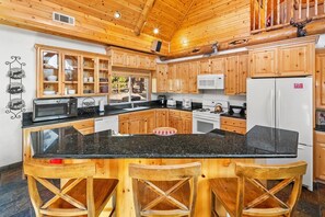Una cocina con armarios de madera, encimera de granito y una isla central con taburetes de bar.