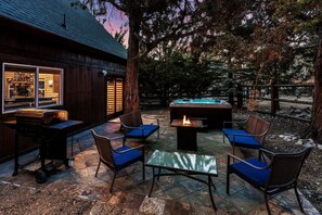 An outdoor patio area with stone flooring, a fire pit, and seating arrangements.
