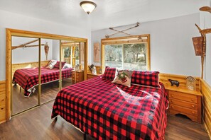 Um quarto acolhedor com uma cama grande, uma cômoda de madeira e um espelho.