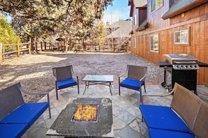 An outdoor patio with a fire pit, seating, and a grill.